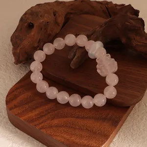 Close-up of pink rose quartz beaded bracelet with carved fox charm and white agate