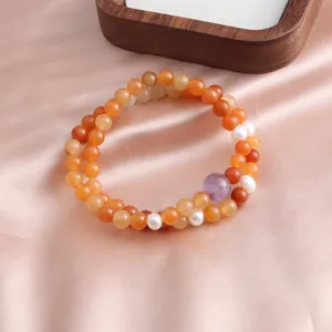 Detail view of a double-strand jade bracelet with orange, white, and purple beads.