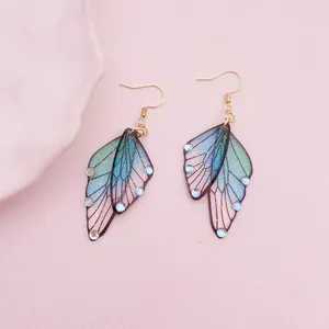 Detailed view of iridescent cicada wing earrings with glitter and gems
