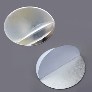 Close-up of round mirror sticker with peeling protective film and adhesive backing for DIY.