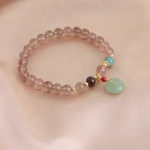 Detailed macro view of a natural strawberry crystal bracelet with a jade-like charm.