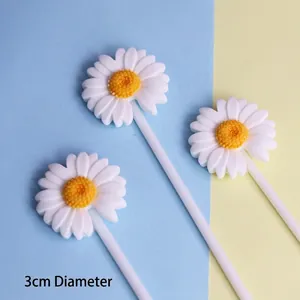 Close-up view of three white daisy resin cake toppers with yellow centers for baking