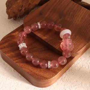 Elegant strawberry crystal beaded bracelet with nine-tailed fox charm shown on wood display