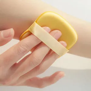 Primo piano di una morbida spugna per trucco a forma di biscotto giallo sulla pelle