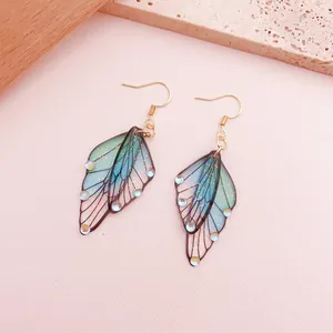 Macro view of translucent cicada wing earrings featuring iridescent glitter and small crystals