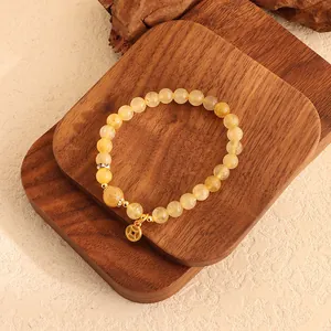 Nahaufnahme eines eleganten Citrin-Perlenarmbands mit traditionellem Goldmünzen-Anhänger.