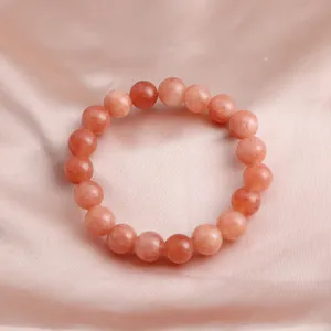 Detailansicht eines natürlichen Sonnenstein-Armbands auf elegantem Pfirsich-Satin