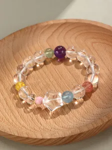 Vue détaillée d'un bracelet en perles de quartz avec breloque étoile sur un plateau en bois