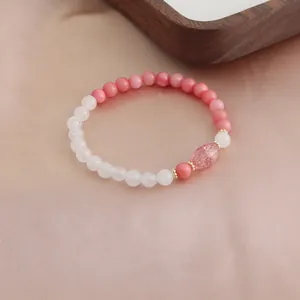 Nahaufnahme von Naturstein-Armband in Rosa auf eleganter Seidenhintergrund-Textur