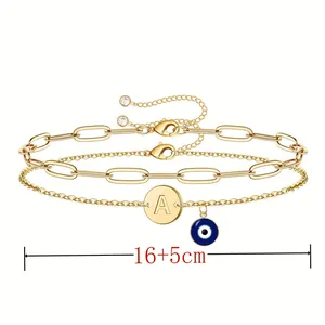 Gold double-layer bracelet with letter A pendant and blue evil eye charm detail