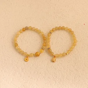 Detailansicht von gelben Citrin- und Rutilquarz-Perlenarmbändern mit goldenen Anhängern