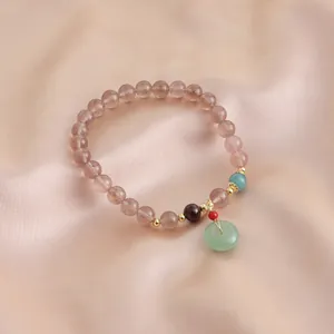 Detail macro view of a natural strawberry quartz bracelet with green jade charm
