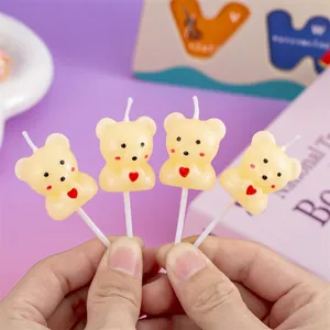 Close-up detail of cute yellow bear candles with red heart for cake decoration