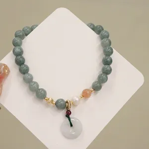 Primo piano di un elegante bracciale di perle di giada verde con perla e ciondolo a ciambella