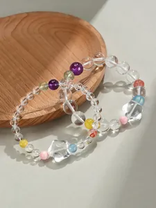 Gros plan de deux bracelets en cristal blanc avec pierres multicolores et étoiles.