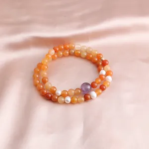 Detailed view of a double-strand gemstone bracelet with orange jade and amethyst beads.