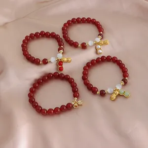 Natürliches Armband aus roten Achatperlen mit goldenem Erdnuss-Anhänger auf Seidenstoff.