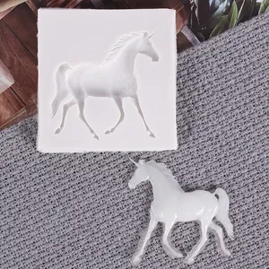 Close-up detail of a white unicorn silicone mold with a finished resin craft figure on grey fabric