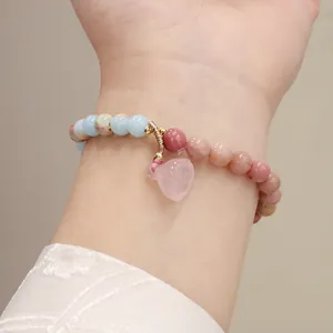 Close-up detail of natural pink quartz lotus pod charm on a beaded stone bracelet