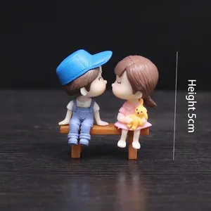 Sweet miniature couple figurines on wooden bench for wedding cake topper ornaments