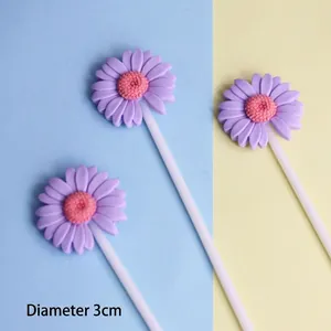 Macro view of purple resin daisy cake toppers with pink centers on white sticks.
