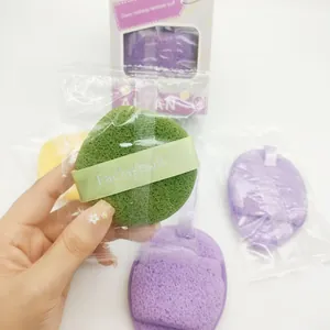 Close-up of a hand holding a green round facial puff from a 3-piece cleansing sponge set.