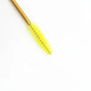 Detail view of a disposable eyelash spoolie brush with yellow bristles and gold handle