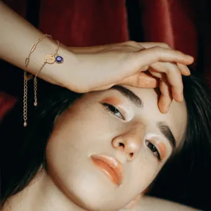 Detailed view of a golden double-layered bracelet with K initial and evil eye charm on model