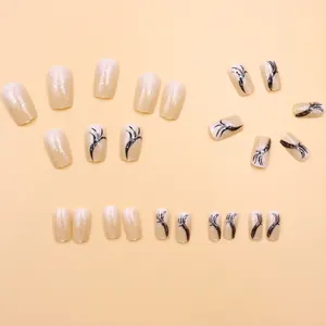 Close-up of nude press-on nails featuring elegant black ribbons and fine silver glitter.