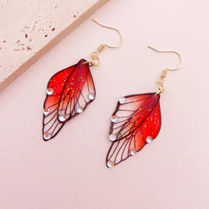 Detailed macro shot of gradient red butterfly wing earrings with sparkling glitter