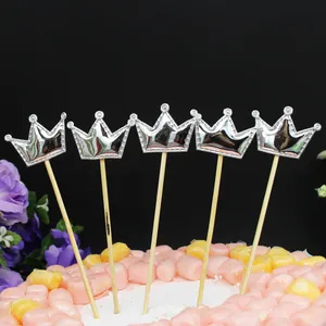 Cinco adornos para tarta con forma de corona plateada en un pastel decorado