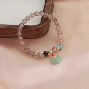 Detail view of strawberry quartz bracelet with green jade donut pendant and gold accents