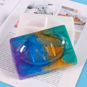 Detail van een kleurrijk glitter harszeepschaaltje naast de witte siliconen gietvorm