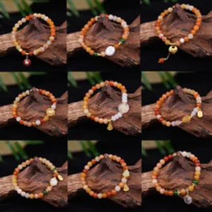 Collection of nine orange agate beaded bracelets with gold charms on wood background.