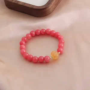 Detailansicht eines natürlichen rosa Rhodochrosit-Armbands mit gelbem Kürbis-Anhänger
