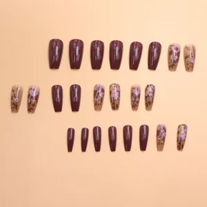 Detailed view of glossy maroon and floral patterned press-on nails on peach background