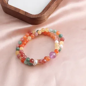 Detail of double-strand multi-color jade and crystal beaded bracelet on pink silk background