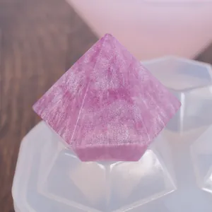 Detalle de un diamante de resina rosa brillante sobre un molde de silicona para manualidad.