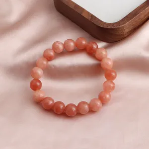 Nahaufnahme natürlicher rötlich-oranger Sonnenstein-Perlen an einem eleganten Kristallarmband
