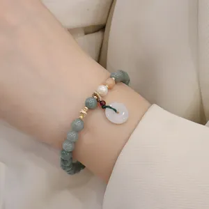 Primo piano di un braccialetto in perline di giada verde con perla e ciondolo in giada