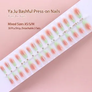 Macro view of 30 gradient peach and mint green press-on nails on a display strip