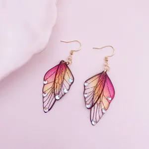 Close-up of elegant handmade butterfly wing earrings with glitter and crystal accents