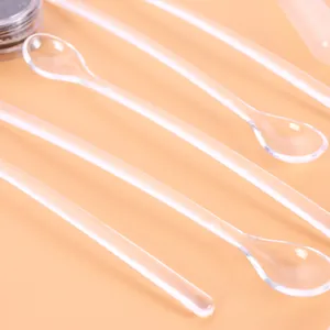 Close-up of clear mini plastic spoons for measuring and mixing DIY resin craft glitter powder.
