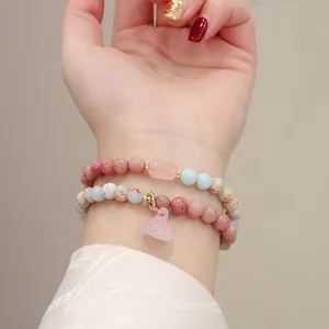 Close-up of elegant natural stone beaded bracelets with rose quartz lotus charm on wrist.