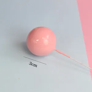 Close-up of a 3cm pink glossy ball cake topper decoration featuring a long thin metal stick.