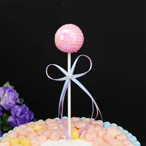 Decorative pink sequined ball cake topper with elegant ribbon bow for birthday party