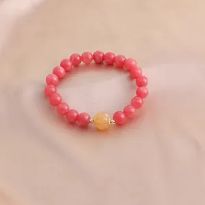 Nahaufnahme eines Armbands aus rosa Kristallperlen mit einer gelben Kürbisperle.
