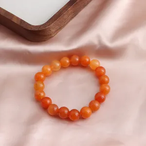 Exquisite Nahaufnahme eines orangefarbenen Sonnenstein-Armbands auf feinem Seidenstoff
