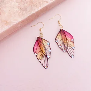 Macro view of semi-transparent cicada wing earrings with pink and yellow gradient