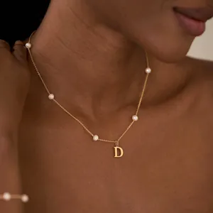 Nahaufnahme einer vergoldeten Kette mit Buchstabe D und echten Süßwasserperlen.
